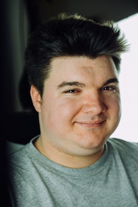 Lukas Krämer steht an eine Wand und sieht freundlich aus