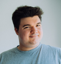 Lukas Krämer steht an eine Wand und sieht freundlich aus